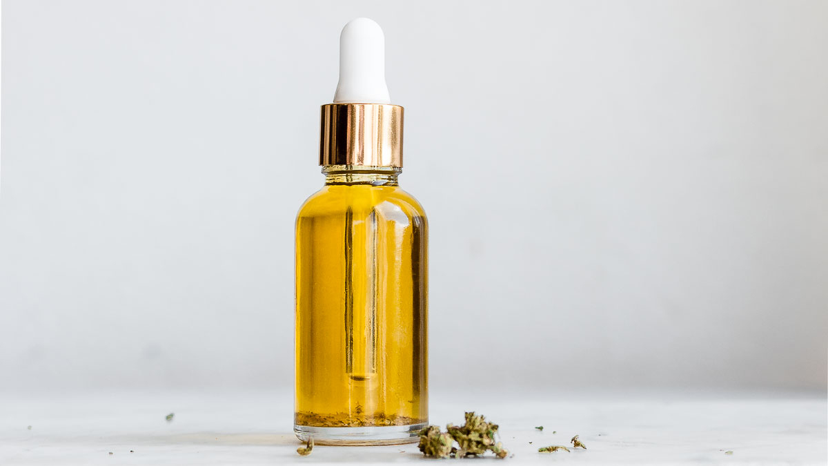 CBD oil bottle with hemp scattered on the table in white background
